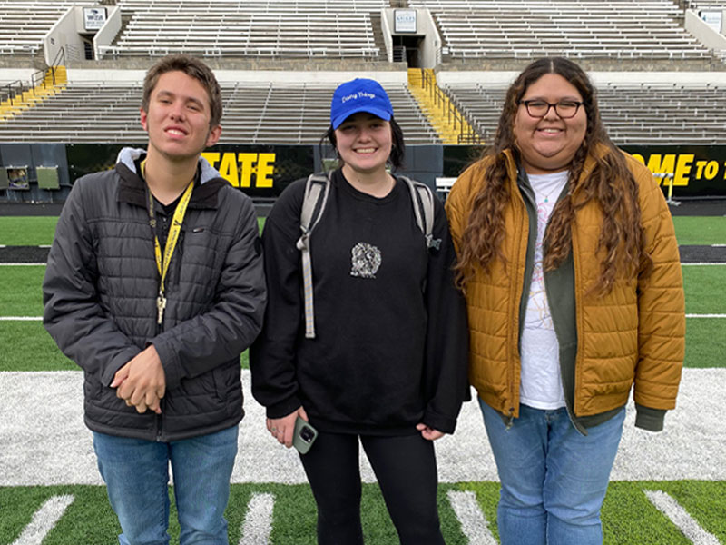 Three SDAP students on football field