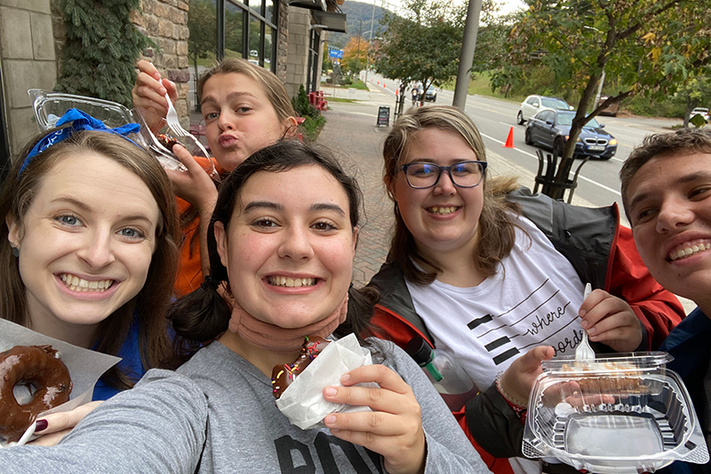 college students eating doughnuts on sidewalk